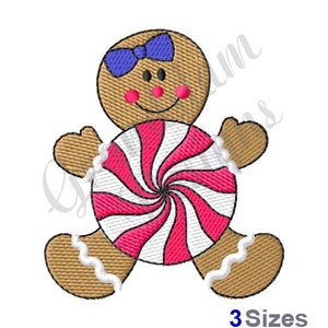 May include: Embroidered gingerbread person with a blue bow, pink cheeks, and a smiling face, holding a red and white swirled candy. The design is on a white background. Text at the bottom reads "3 Sizes".