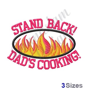 May include: Embroidered design with the text "Stand Back! Dad's Cooking!" in pink lettering with a black oval around a yellow and orange flame design.