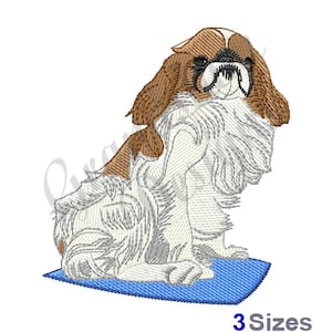 May include: Embroidered design of a brown and white Pekingese dog sitting on a blue mat. The dog has a serious expression and is looking directly at the viewer.