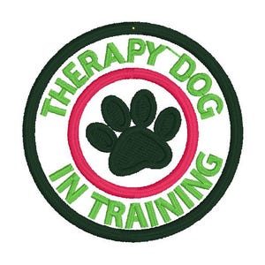 May include: Embroidered patch with a green paw print inside a red circle, surrounded by the text "THERAPY DOG IN TRAINING" in green on a white background, framed by a dark green border.