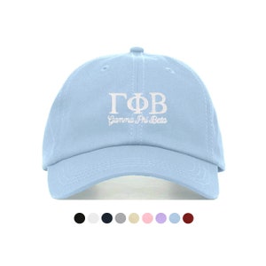 Peut inclure: Une casquette de baseball bleu clair avec une broderie blanche qui dit "ΓΦΒ Gamma Phi Beta".