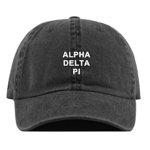 May include: A black distressed denim baseball cap with white embroidered text that reads "ALPHA DELTA PI".