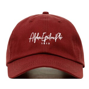 Puede incluir: Una gorra de béisbol de color granate con texto bordado en blanco que dice "Alpha Epsilon Phi 1913".
