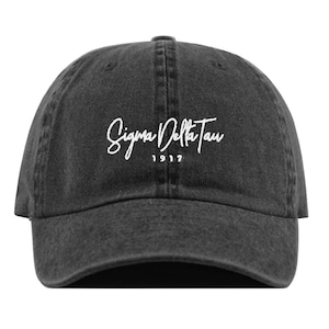 Puede incluir: Una gorra de béisbol de denim negro desgastado con texto bordado en blanco que dice "Sigma Delta Tau 1917".
