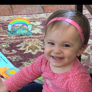 May include: A young child wearing a pink polka dot shirt and blue pants sits on a patterned rug and reads a book titled "Who lives in the desert?"