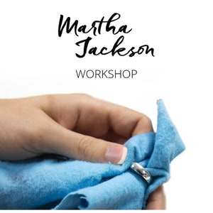 May include: A hand holding a silver ring and polishing it with a light blue cloth. The text "Martha Jackson WORKSHOP" is at the top of the image.
