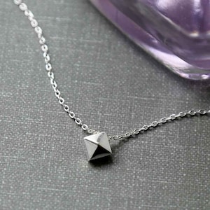 以下が含まれることがあります： 小さな銀のピラミッド型のペンダントが付いた銀のチェーンネックレス