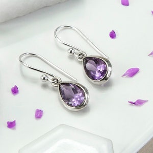 May include: A pair of silver teardrop earrings with purple amethyst gemstones.