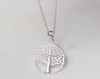 Puede incluir: Collar plateado con un colgante redondo que representa un árbol. El diseño del árbol es intrincado y abierto, dentro de un marco redondo. La cadena es fina y el colgante es de metal plateado.
