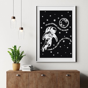 Może przedstawiać: Czarno-biały oprawiony wydruk przedstawiający astronautę w kosmosie, otoczonego gwiazdami i księżycem. Tekst brzmi: "Jestem astronautą, ty jesteś księżycem. Wpatruję się w ciebie, śpiewam dla ciebie, krążę wokół ciebie."