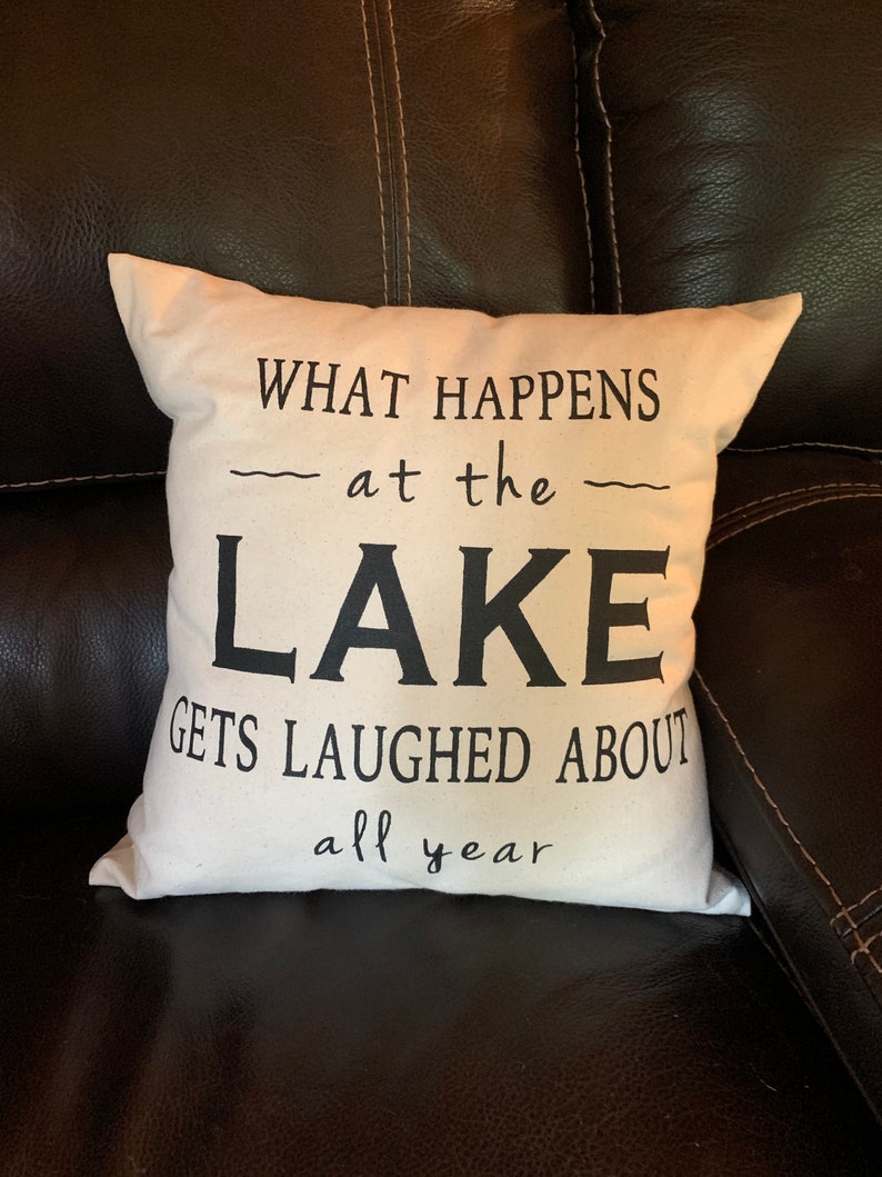 May include: White throw pillow with black text that reads "What happens at the lake gets laughed about all year".