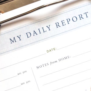 K&ouml;nnte beinhalten: Ein wei&szlig;er Klemmbrett mit dem Text "MY DAILY REPORT" in blauer Schrift. Das Klemmbrett hat einen Bereich f&uuml;r "DATE:" und "NOTES from HOME:" mit Zeilen zum Schreiben.
