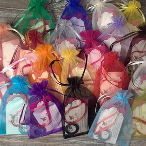 K&ouml;nnte beinhalten: Sortiment von bunten Organzas&auml;ckchen mit einem kleinen Etikett, auf dem "Griffin Lily" in wei&szlig; steht. Die S&auml;ckchen sind mit kleinen runden Gegenst&auml;nden gef&uuml;llt.