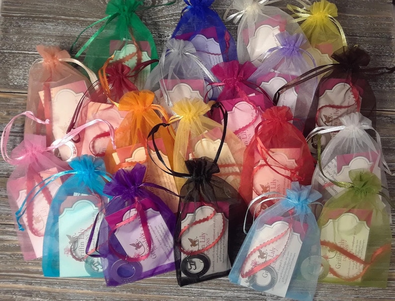 K&ouml;nnte beinhalten: Sortiment von bunten Organzas&auml;ckchen mit einem kleinen Etikett, auf dem "Griffin Lily" in wei&szlig; steht. Die S&auml;ckchen sind mit kleinen runden Gegenst&auml;nden gef&uuml;llt.