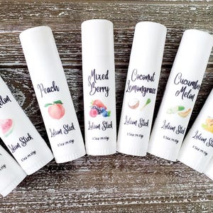 Pode incluir: Sete tubos brancos de protetor labial com v&aacute;rias etiquetas de frutas e sabores. Os sabores incluem Blueberry Muffin, Watermelon, Peach, Mixed Berry, Coconut Lemongrass, Cucumber Melon, Tropical Fruit e Orange. Cada tubo tem uma ilustra&ccedil;&atilde;o de fruta.