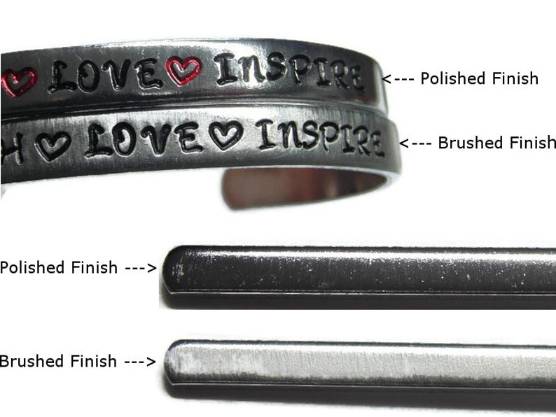 May include: Two silver bracelets with the words "LOVE" and "INSPIRE" engraved on them. The top bracelet has a polished finish, while the bottom bracelet has a brushed finish.