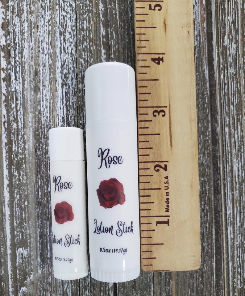 Pode incluir: Duas barras de lo&ccedil;&atilde;o brancas com a inscri&ccedil;&atilde;o "Rose Lotion Stick" e uma rosa vermelha. A barra maior tem cerca de 10 cm de altura, e a menor 5 cm. A barra maior cont&eacute;m 14,17 g.