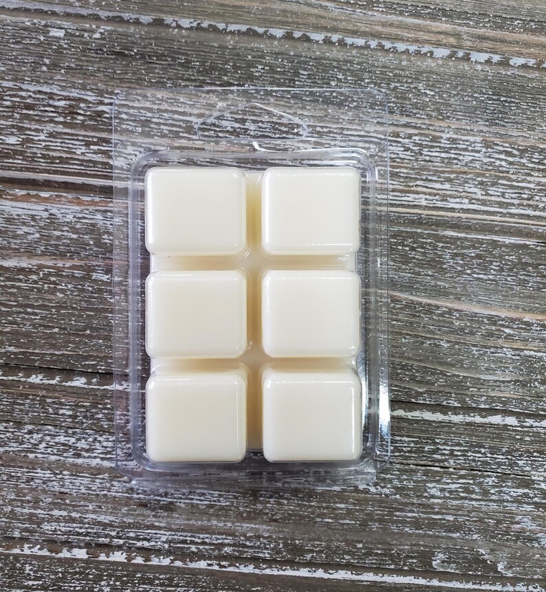 May include: A clear plastic tray with six square wax melts. The wax melts are white and are arranged in a 2x3 grid.