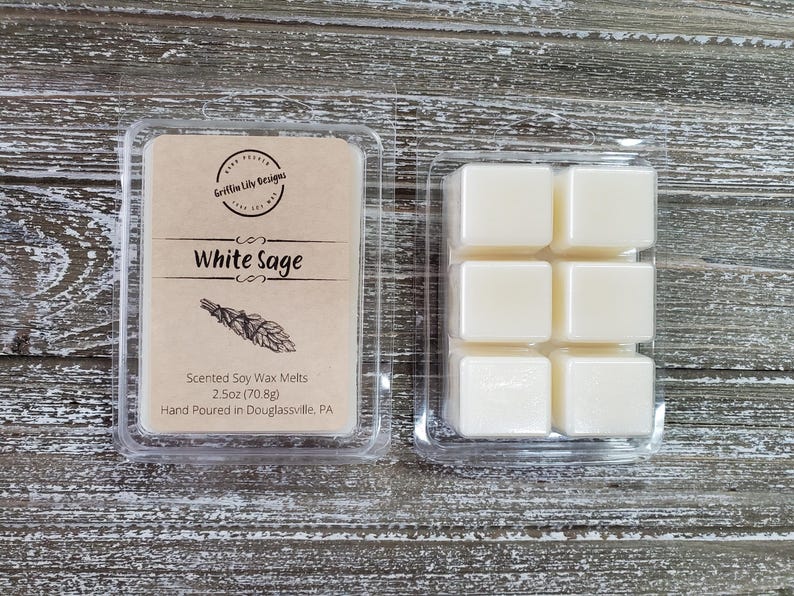 May include: A clear plastic container of six white soy wax melts, labeled "White Sage" with the text "Scented Soy Wax Melts 2.5oz (70.8g) Hand Poured in Douglassville, PA".