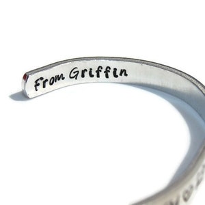 May include: A silver bracelet with the inscription "From Griffin" on the inside.