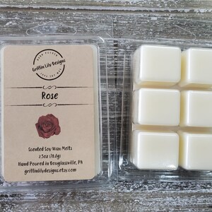 May include: A clear plastic container holding six square wax melts and a label. The label reads "Rose" with a rose graphic and "Griffin Lily Designs". The wax melts are scented soy wax, 2.5 oz (70.8g).