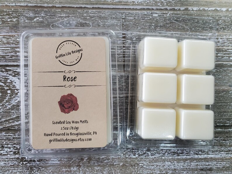 May include: A clear plastic container holding six square wax melts and a label. The label reads "Rose" with a rose graphic and "Griffin Lily Designs". The wax melts are scented soy wax, 2.5 oz (70.8g).