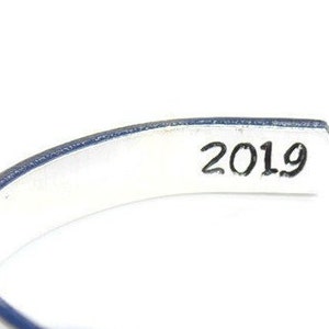 May include: Silver bracelet with a blue edge and the year 2019 engraved on the inside.