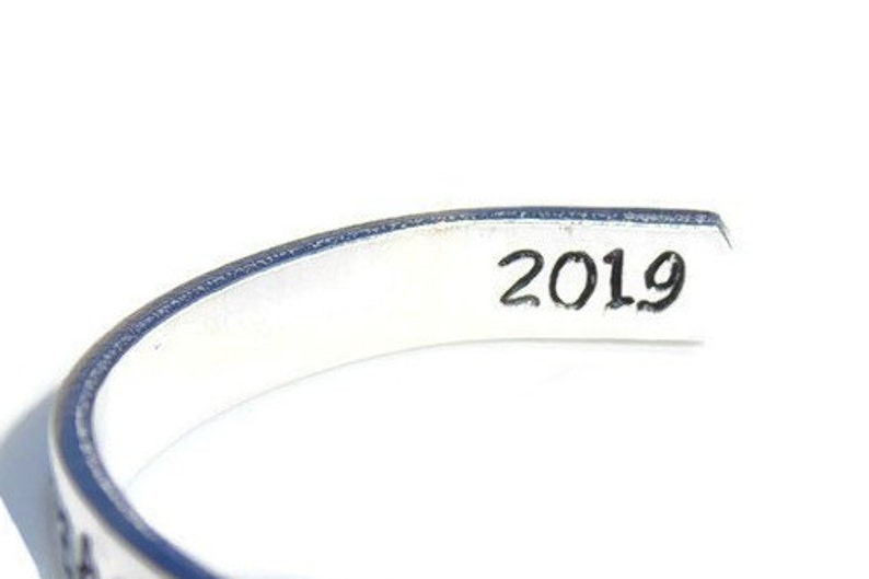 May include: Silver bracelet with a blue edge and the year 2019 engraved on the inside.