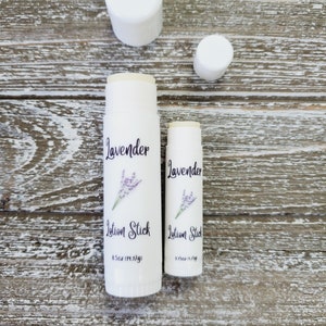 Pode incluir: Dois bast&otilde;es de lo&ccedil;&atilde;o brancos com a palavra "Lavanda" e um gr&aacute;fico de raminho de lavanda. O texto "Lotion Stick" est&aacute; abaixo da palavra "Lavanda". O bast&atilde;o maior tem 14,17g. Duas tampas brancas tamb&eacute;m est&atilde;o na imagem.