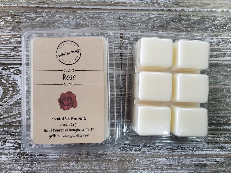 May include: Clear plastic packaging containing scented soy wax melts. The label reads "Rose" with a rose graphic. The package contains six square wax cubes. The label also includes the text "Griffin Lily Designs".