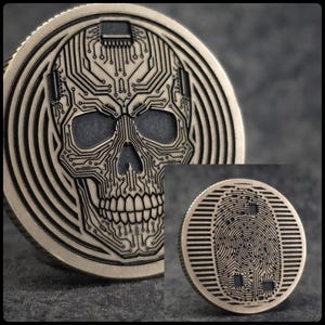 May include: A round, metallic coin featuring a detailed skull design composed of circuit board patterns. The coin has a dark, aged finish with concentric circles radiating from the skull. A smaller inset coin shows a fingerprint design.
