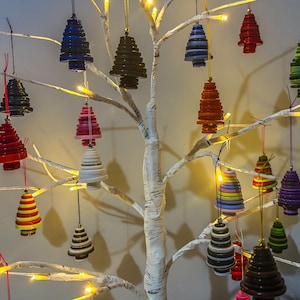 May include: A white birch tree branch decorated with colourful Christmas ornaments shaped like Christmas trees. The ornaments are made of layered circles of different colours and patterns.