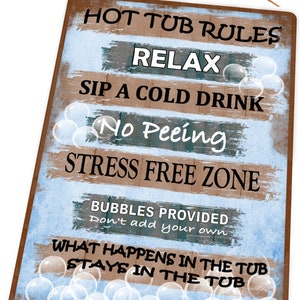 Op de afbeelding: Een rustiek houten bord met blauwe en bruine verf, met regels voor de hottub. Het bord luidt "Hot Tub Rules", "Relax", "Sip a Cold Drink", "No Peeing", "Stress Free Zone", "Bubbles Provided Don't add your own", "What Happens in the Tub Stays in the Tub".