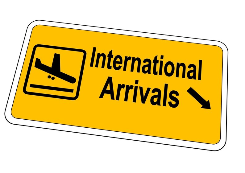 May include: Yellow sign with a black airplane icon and the text "International Arrivals" with a black arrow pointing to the right.