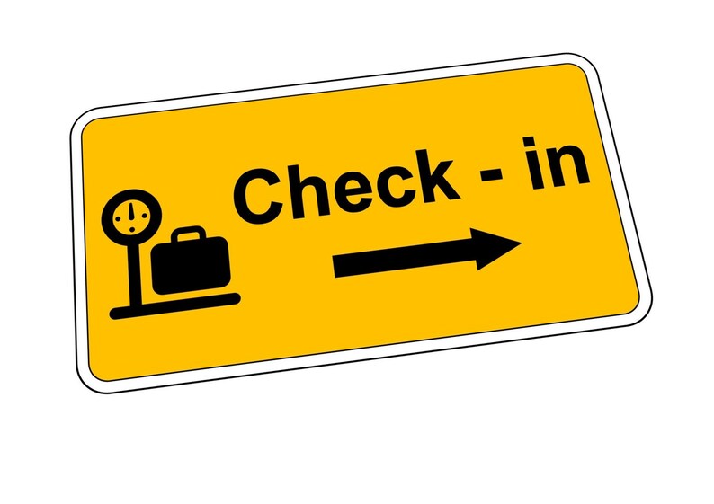 May include: Yellow sign with black text and an arrow pointing right. The sign says "Check - in" and has a black silhouette of a suitcase on a scale.