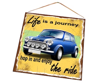 Puede incluir: Un letrero de metal de estilo vintage con fondo amarillo y un coche Mini Cooper azul. El letrero dice "La vida es un viaje, súbete y disfruta del paseo."