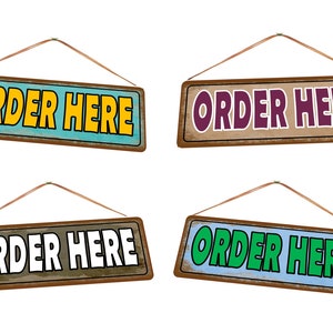 Op de afbeelding: Vier rechthoekige houten borden met de tekst "ORDER HERE" in verschillende kleuren. De borden zijn bruin met een verweerde uitstraling en de tekstkleuren zijn geel, paars, wit en groen. Elk bord is opgehangen aan een bruin touwtje.