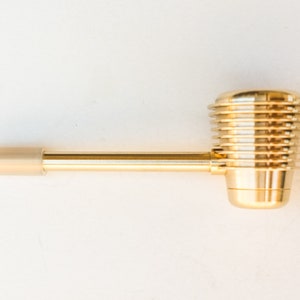 K&ouml;nnte beinhalten: Eine goldene Metallpfeife mit einem langen, geraden Schaft und einer runden, gerippten Schale.
