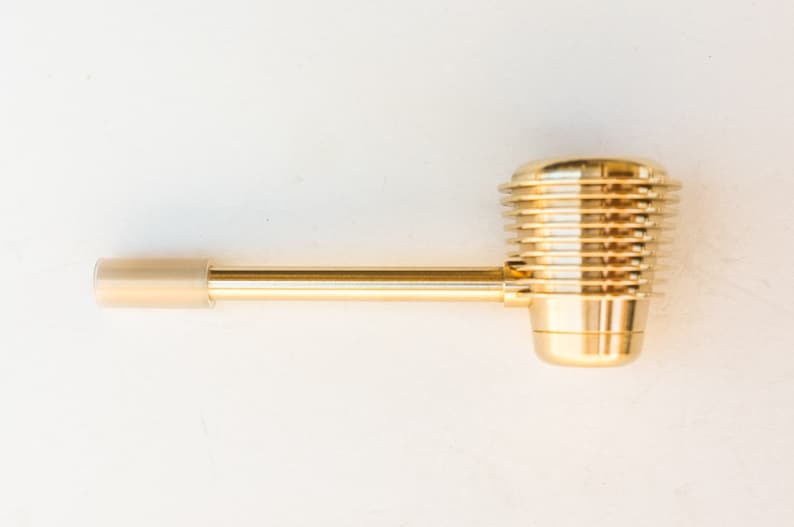 K&ouml;nnte beinhalten: Eine goldene Metallpfeife mit einem langen, geraden Schaft und einer runden, gerippten Schale.