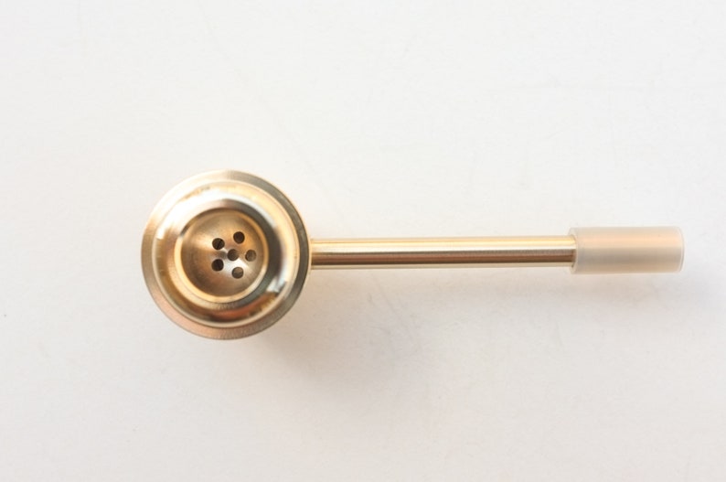 K&ouml;nnte beinhalten: Eine goldene Metall-Rauchpfeife mit einer runden Schale und einem langen, geraden Schaft. Die Schale hat eine Reihe kleiner L&ouml;cher f&uuml;r den Luftstrom. Der Schaft hat ein klares Plastikmundst&uuml;ck.