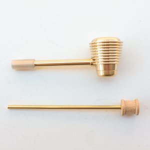 K&ouml;nnte beinhalten: Eine goldene Metall-Rauchr&ouml;hre mit einem Holzstiel. Die Pfeife hat einen zylindrischen Kopf mit einem gerippten Design.