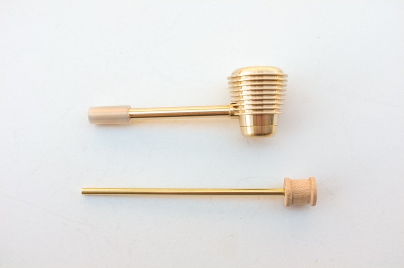 K&ouml;nnte beinhalten: Eine goldene Metall-Rauchr&ouml;hre mit einem Holzstiel. Die Pfeife hat einen zylindrischen Kopf mit einem gerippten Design.