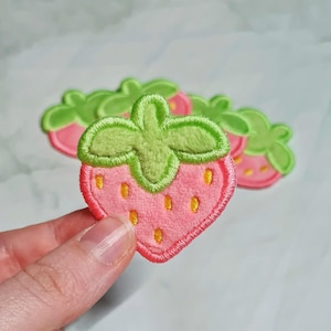 May include: Five pink and green felt strawberry patches with embroidered details.