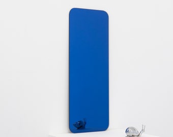 May include: A blue rectangular mirror with rounded edges is standing on a white surface. A silver snail figurine is in front of the mirror.
