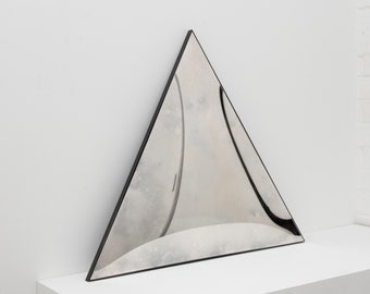 Pode incluir: Um espelho triangular com moldura preta. O espelho reflete o ambiente circundante, criando uma imagem distorcida.