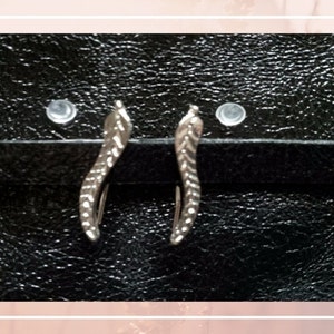 May include: A pair of silver earrings with a leaf design. The earrings are on a black background.
