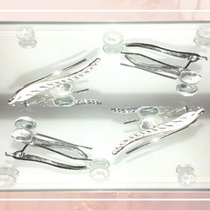 May include: A pair of silver earrings with a leaf design. The earrings are delicate and have a simple, elegant style.