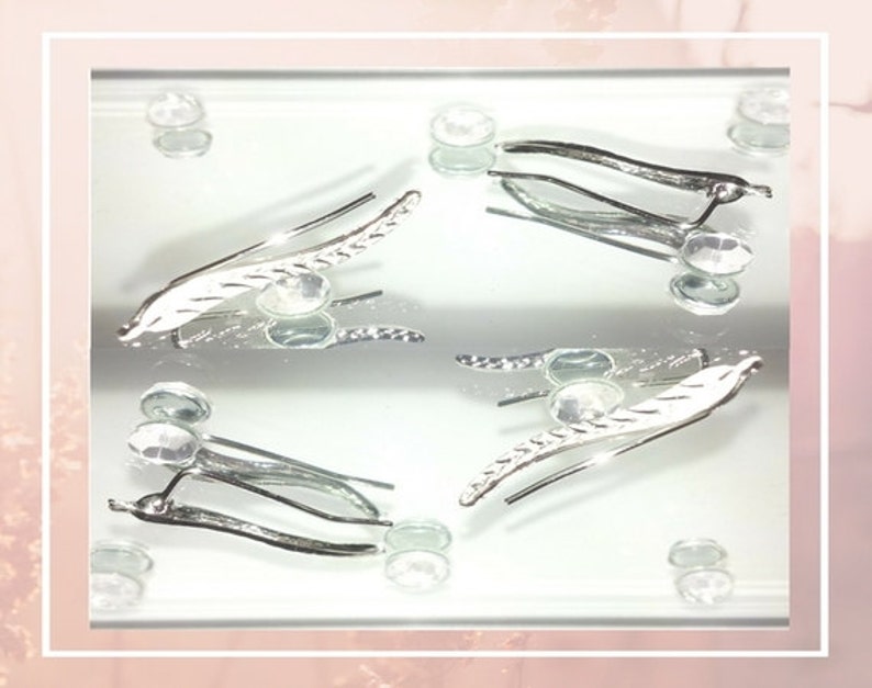 May include: A pair of silver earrings with a leaf design. The earrings are delicate and have a simple, elegant style.