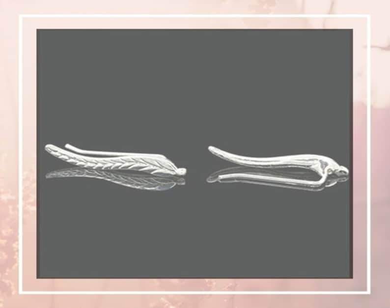 May include: A pair of silver ear cuffs, one shaped like a leaf and the other a curved line.