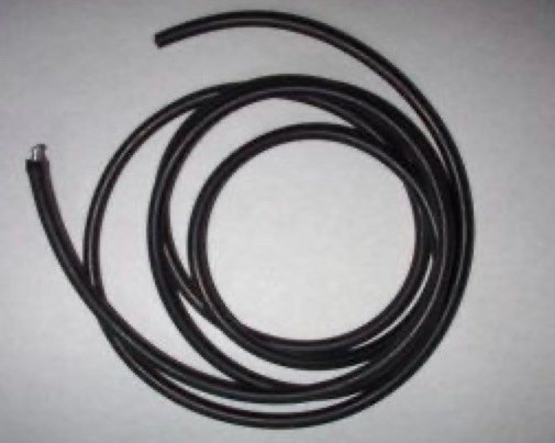 May include: A black rubber cord coiled up on a white surface.